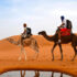 Two people riding camels in desert Morocco
